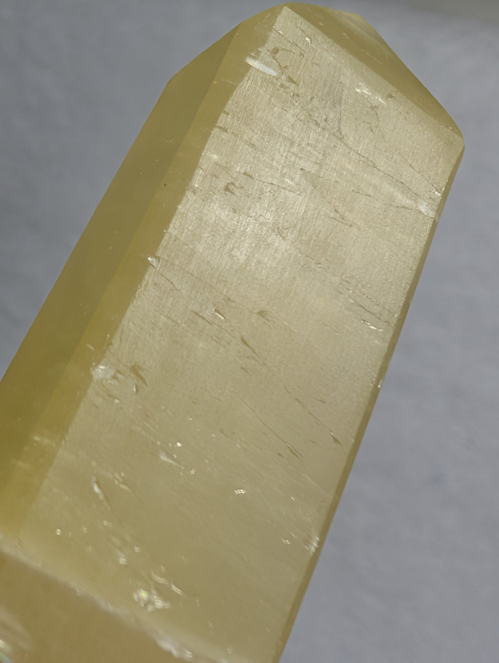 Lemon Calcite Tower by Syn's Crystal Co showing a vibrant yellow crystal point on a neutral background.