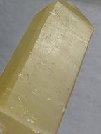 Lemon Calcite Tower by Syn's Crystal Co showing a vibrant yellow crystal point on a neutral background.