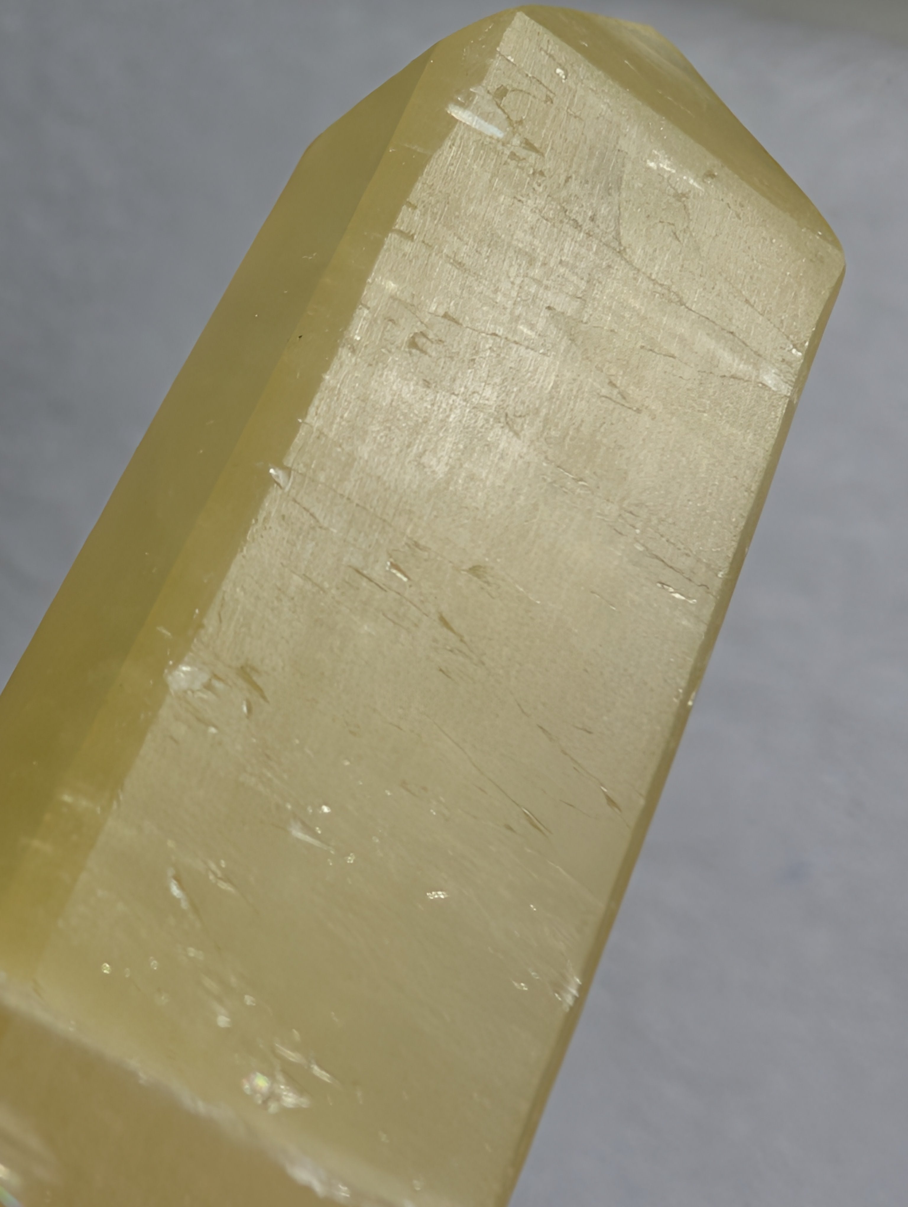 Lemon Calcite Tower by Syn's Crystal Co showing a vibrant yellow crystal point on a neutral background.