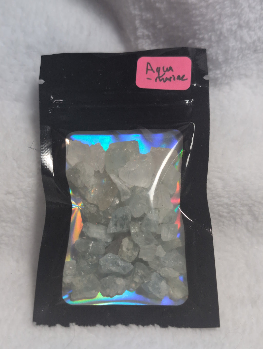 Bag of raw Mookaite crystal chips from Syn's Crystal Co, showing colorful, irregular-shaped natural stone pieces inside a clear bag.