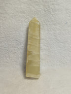 Lemon Calcite tower crystal for Solar Plexus Chakra, showing a yellow calcite point with natural striations and a polished finish.