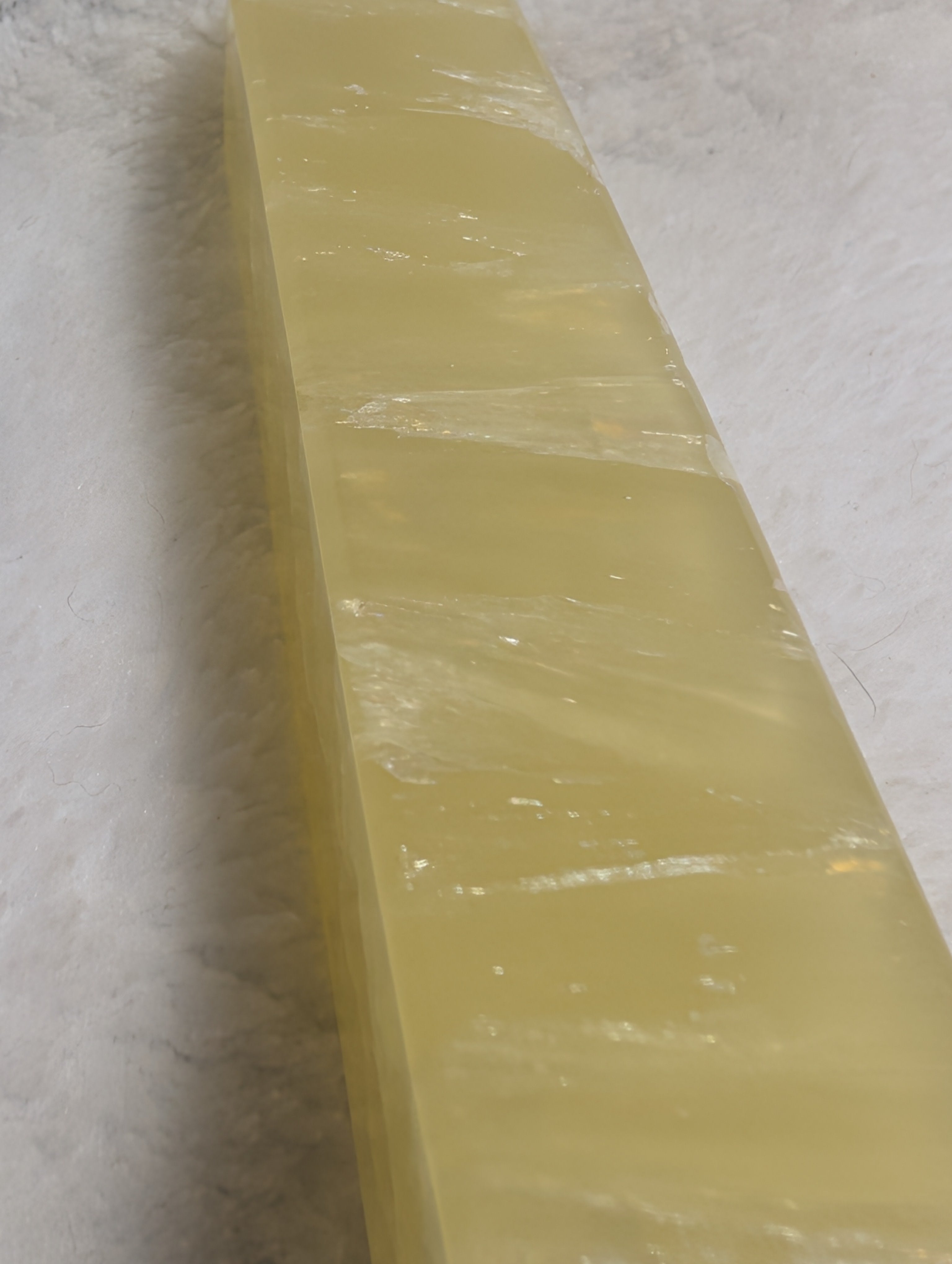 Lemon Calcite Tower from Syn's Crystal Co, showcasing a vibrant yellow crystal point with smooth, polished surface and natural mineral details.