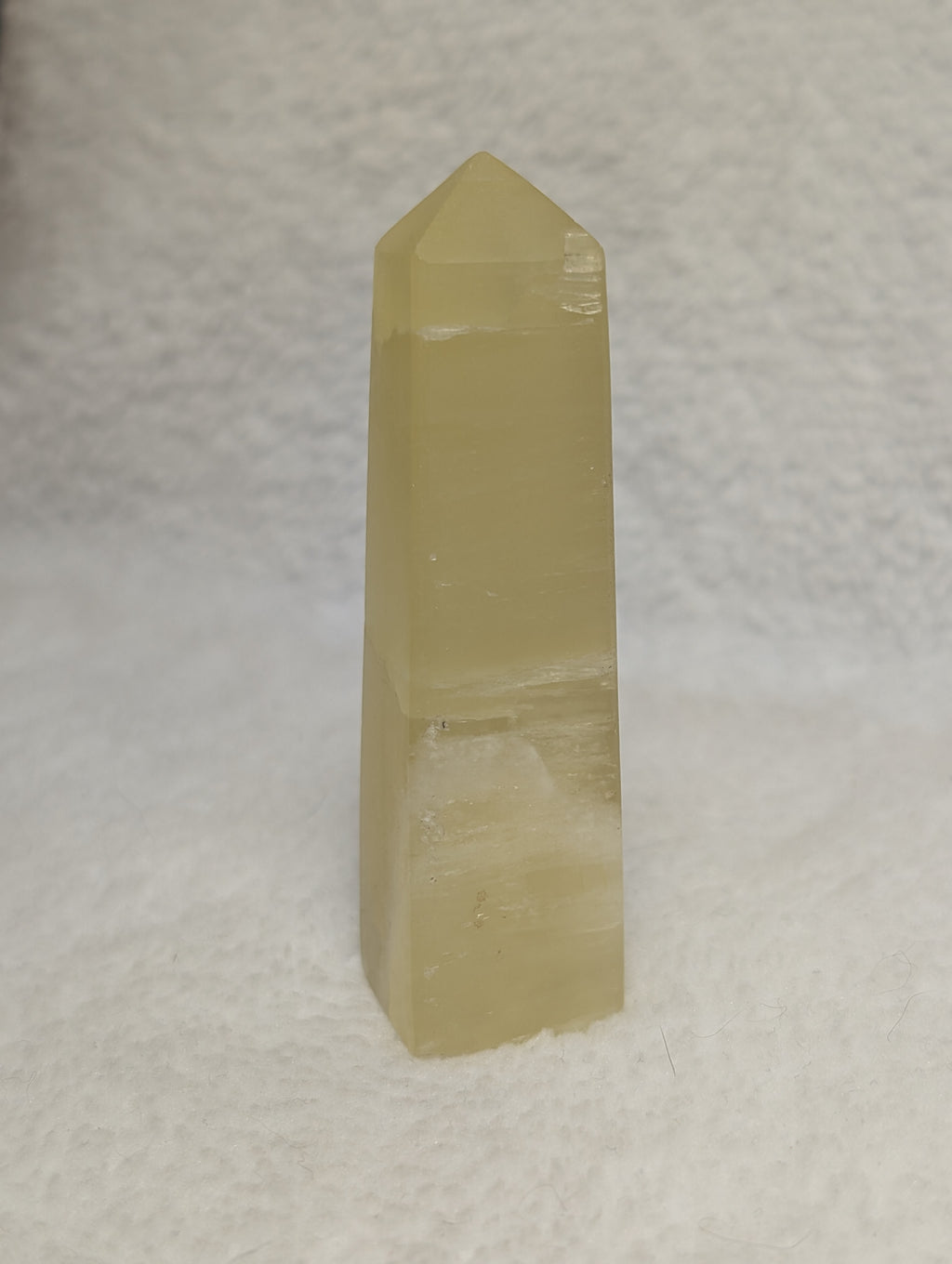 Lemon Calcite Tower by Syn's Crystal Co, a polished yellow crystal with natural striations and a pointed shape.