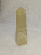 Lemon Calcite Tower by Syn's Crystal Co, a polished yellow crystal with natural striations and a pointed shape.
