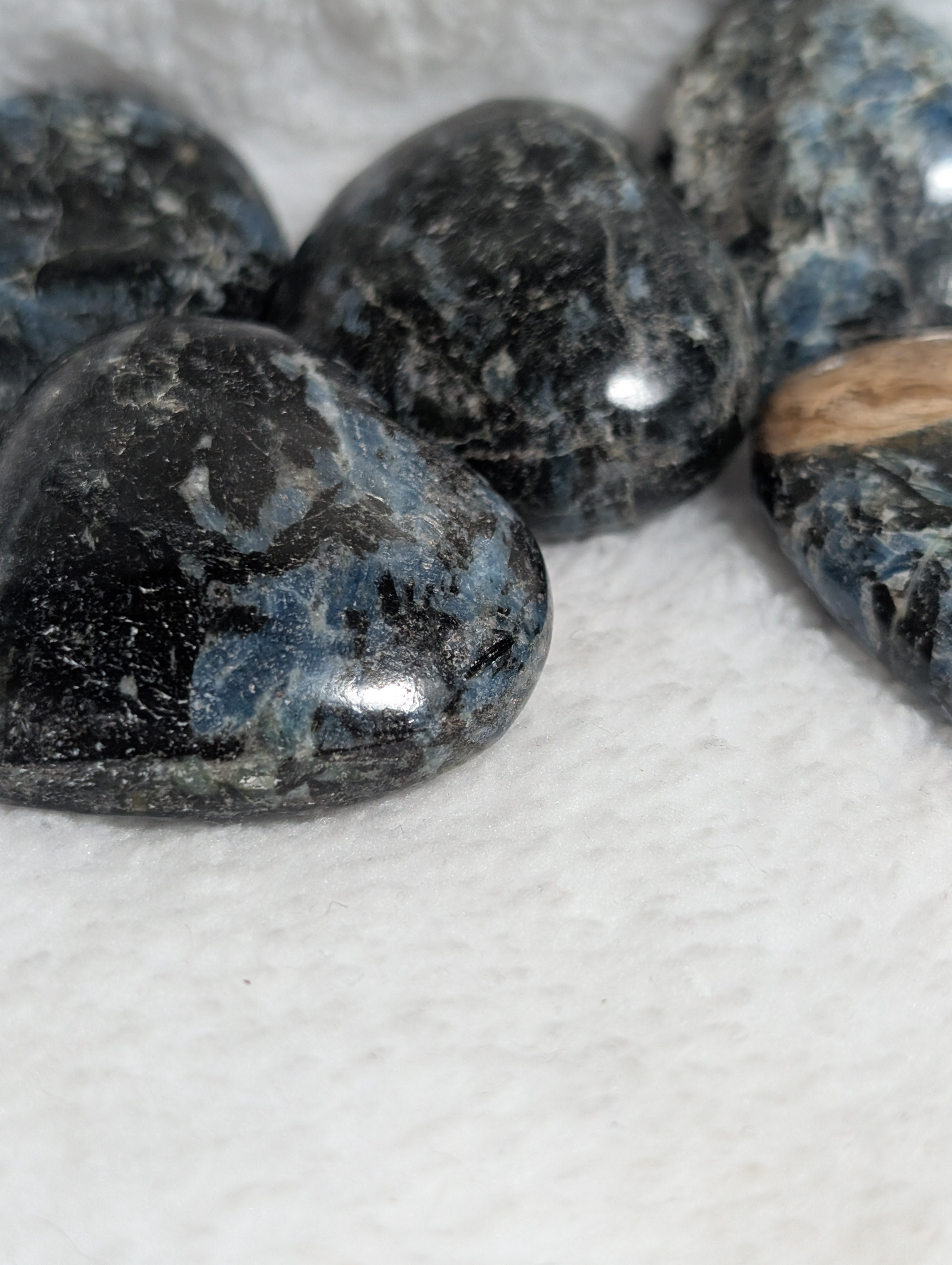 Blue Apatite and black tourmaline heart palm stones from Syn's Crystal Co, featuring polished, smooth gemstone hearts.