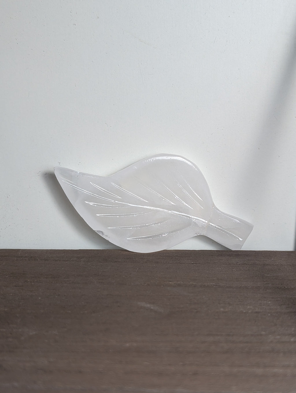 Silky white calcite leaf carving by Syn's Crystal Co, showcasing detailed natural stone craftsmanship and leaf shape.