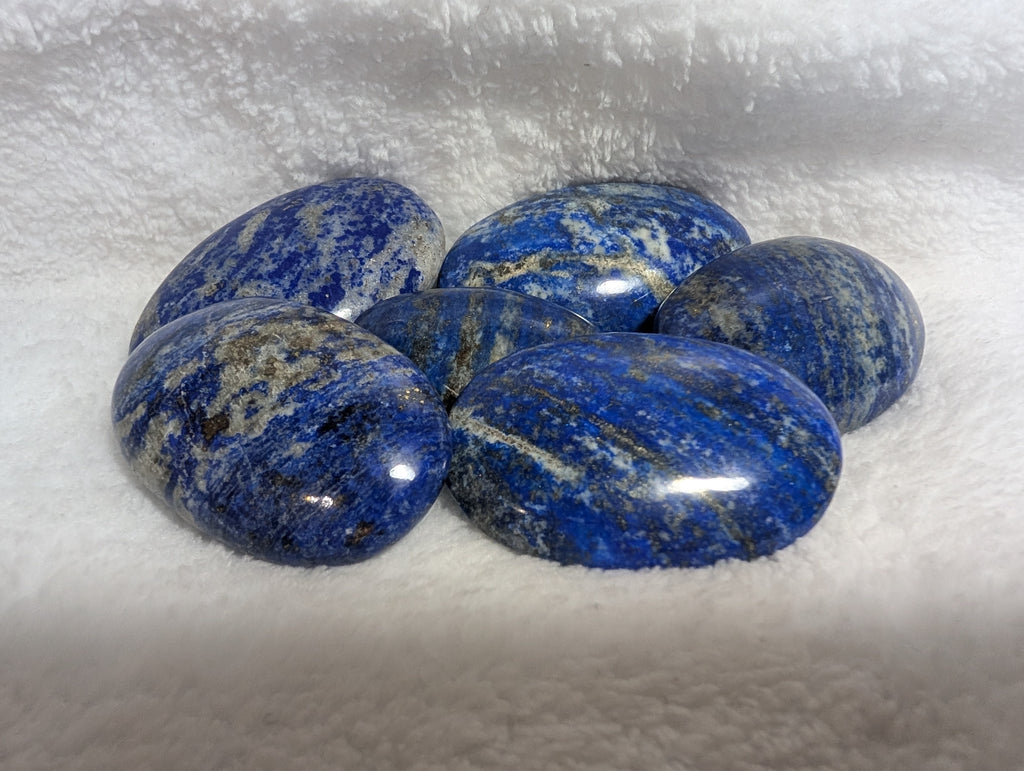 Lapis Lazuli palmstone from Syn's Crystal Co, smooth blue gemstone with gold flecks, used for meditation and energy healing.